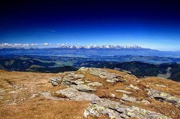 Wide angle panorama of Western and High Tatra ranges, green forests of Vah and Poprad valleys under blue sky in a spring sunny day from barren grassy Kralova Hola peak Low Tatras Slovakia Europe © nogreenabove2k