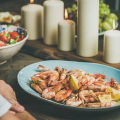 Holiday celebration table setting with snacks. Salad, shrimps and candles on wooden table, square crop