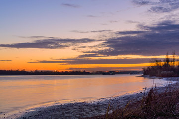Scenic sky over the river at sunset time. View from the shore