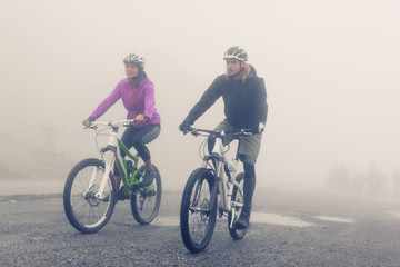 Young Couple Cycling Through Fog