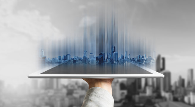 Hand holding digital tablet with futuristic modern buildings hologram on screen
