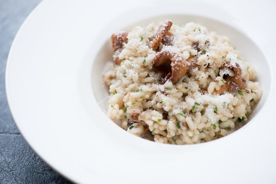 Closeup of risotto with chanterelle mushrooms served in a white plate, selective focus