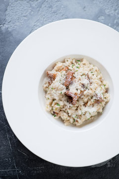 Above view of risotto with chanterelles and parmesan in a white plate, vertical shot