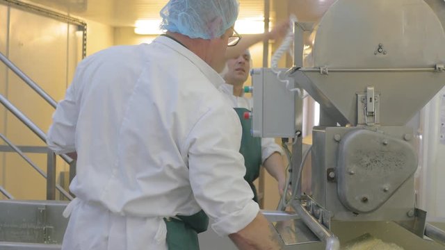 Team of factory employees starts cheese milling process