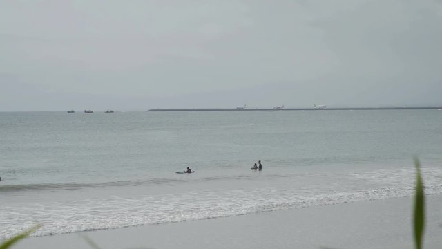 Airplane landing on island Bali airport under blue sea with waves on horizon