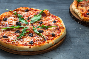 Homemade pizza with tomato, salumi, arugula and olives. Top view stone background