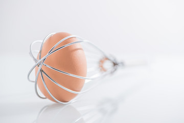 Fototapeta na wymiar Egg trapped in whisk
