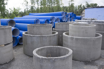 Concrete ring wells with different diameters and gray lie in the street