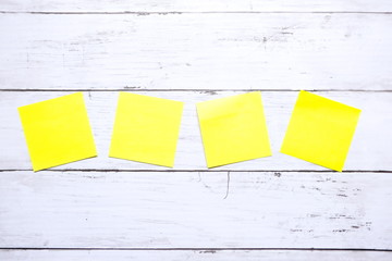 Business and miscellaneous theme. Top view of four empty yellow sticky notes on wooden background....