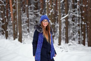 Fototapeta na wymiar girl in blue knitted scarf with hat in winter forest.