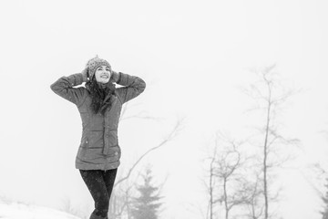 Young  woman walking in a nature park and breathing fresh winter air feeling wonderful at weekend. Young hipster girl wear blue coat and grey knitted hat in winter weather having fun outdoors