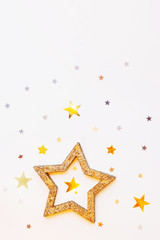 Christmas and New Year background with sparkling golden star and confetti. Holiday symbols on white background with place for text.
