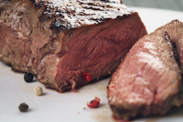 sliced beef steack with pepper on white plate closeup