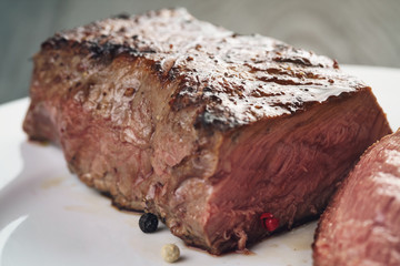 sliced beef steack with pepper on white plate closeup