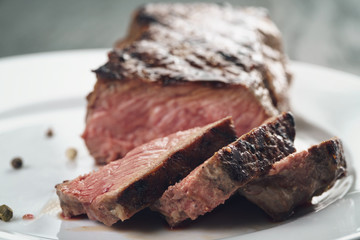 sliced beef steack with pepper on white plate closeup