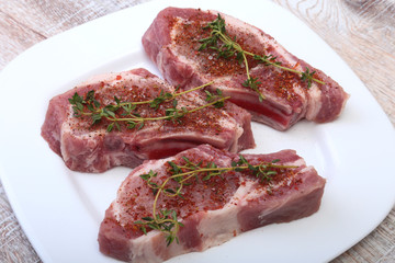 Raw pork chops, spices and rosemary on cutting board. Ready for cooking.