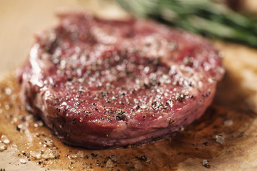 fresh raw rib eye steak in spices on wood board on kitchen table