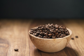 roasted coffee beans in wood bowl on table with dark background