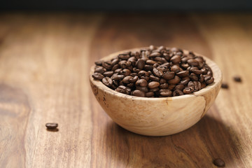 roasted coffee beans in wood bowl on table with dark background