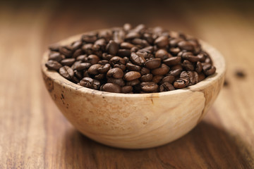 roasted coffee beans in wood bowl on table with dark background