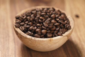 roasted coffee beans in wood bowl on table with dark background