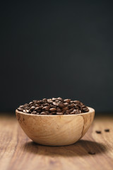roasted coffee beans in wood bowl on table with dark background
