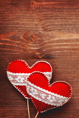 Two felt hearts with laces, symbol of love, on wooden background. Good for Valentine's Day cards. Place for text.