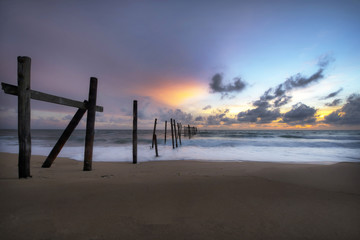 The old wooden bridge on beach in sunset