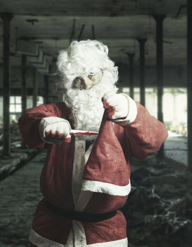 Horror Zombie Weihnachtsmann schneidet seine Weihnachtsmütze mit dem blutverschmiertes Messer