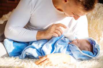 happy Father Feeding Newborn Baby At Home