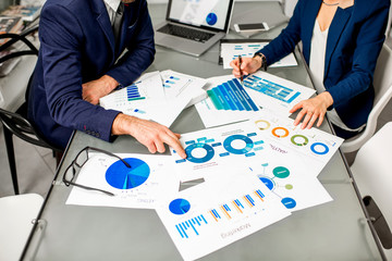 Marketer or analityc manager team working on paper charts at the table. Image focused on the documents with no face