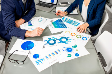 Marketer or analityc manager team working on paper charts at the table. Image focused on the...