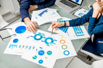 Marketer or analityc manager team working on paper charts at the table. Image focused on the...