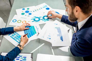 Marketer or analityc manager team working on paper charts at the table. Image focused on the documents