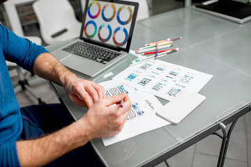 UX designer working on the mobile application experience sketching drawings at the office. Image...