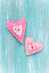 Valentine's Day concept with two handmade pink felt hearts on turquoise color wooden background