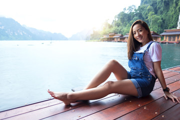 Fototapeta na wymiar asian beautiful girl sit a relaxing in the lake a rainy season with sunrise light