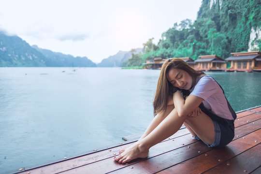 asian beautiful girl sit a relaxing in the lake a rainy season with sit sleep eye