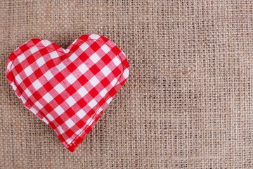 Valentines Day background. Handmade checkered fabric heart on sackcloth, copy space