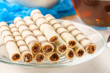 Striped wafer rolls, delicious chocolate snack on white wooden table.