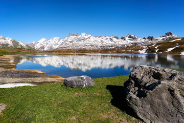 Bergpanorama Tannensee Bergsee Spiegelungen Melchsee-Frutt Titlis wolkenloser Himmel Wiese Felsbrocken