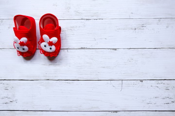 Top view of cute red baby shoe on white  wooden background with copy space.