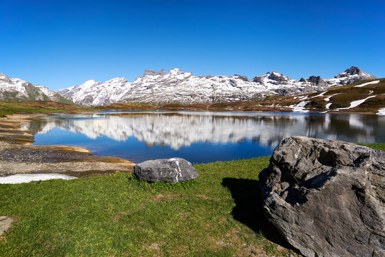 Bergpanorama Tannensee Bergsee Spiegelungen Melchsee-Frutt Titlis wolkenloser Himmel Wiese Felsbrocken