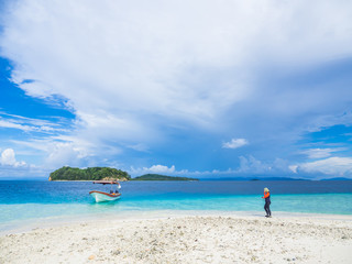 Abstract nature background, cloudy day, turquoise sea, clean sandy beach, boat and traveler.