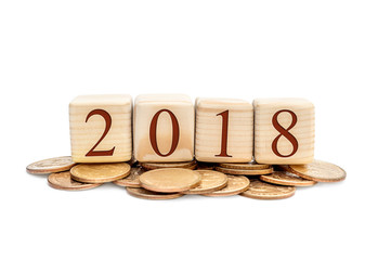 Wooden cubes with numbers 2018 on heap of coins.
