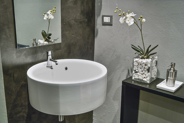 the sink suspended in the modern bathroom and the orchid on the shelf