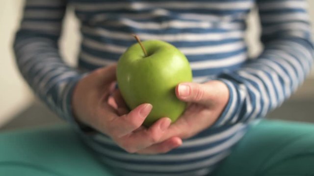Pregnant woman holding green apple as symbol of health