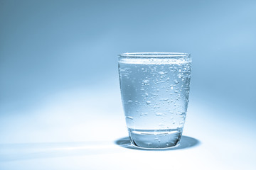 Glass with water and water drops on a blue background