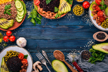 Healthy food. Black rice, buckwheat, avocado, cherry tomatoes, green peas and hazelnut. On a wooden background. Top view. Free space for your text.