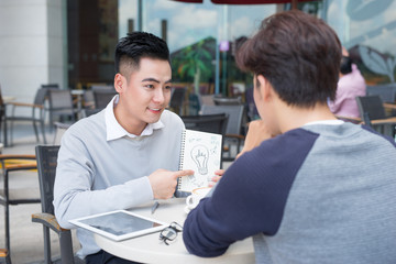 Obraz premium Two cheerful asian business people discussing with documents